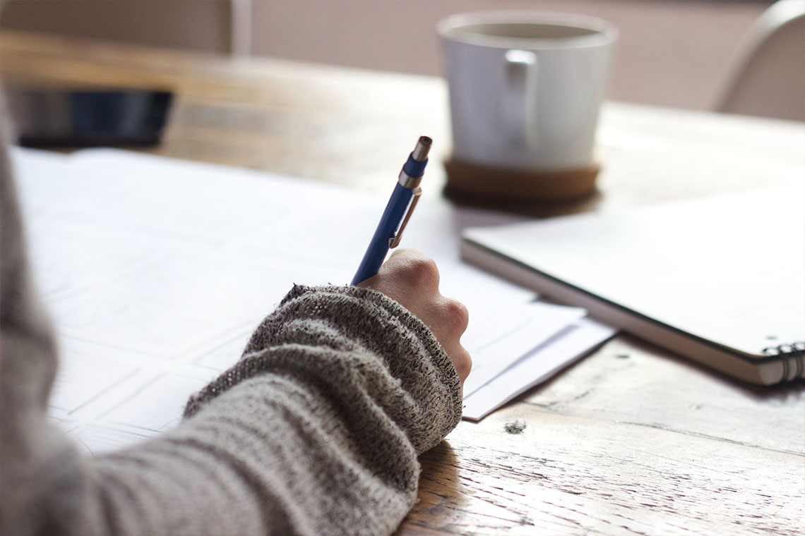 Person schreibt mit Stift auf Papier